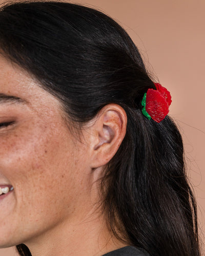 Close-up of a person with a red flower in their hair against a beige background