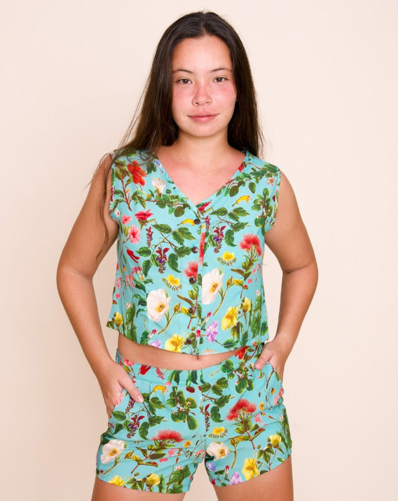 Women's Mohala Cropped Vest featuring botanical illustrations of native Hawaiian flowers. Soft and comfortable bamboo fiber rayon. Sleeveless button-down top. Kai (blue) color.